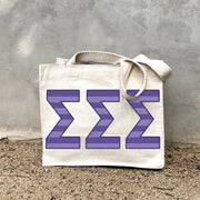 Model carrying the Sigma Sigma Sigma Greek letters in sorority colors small striped tote.