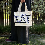 Model carrying the Sigma Delta Tau small black and white stripe tote.