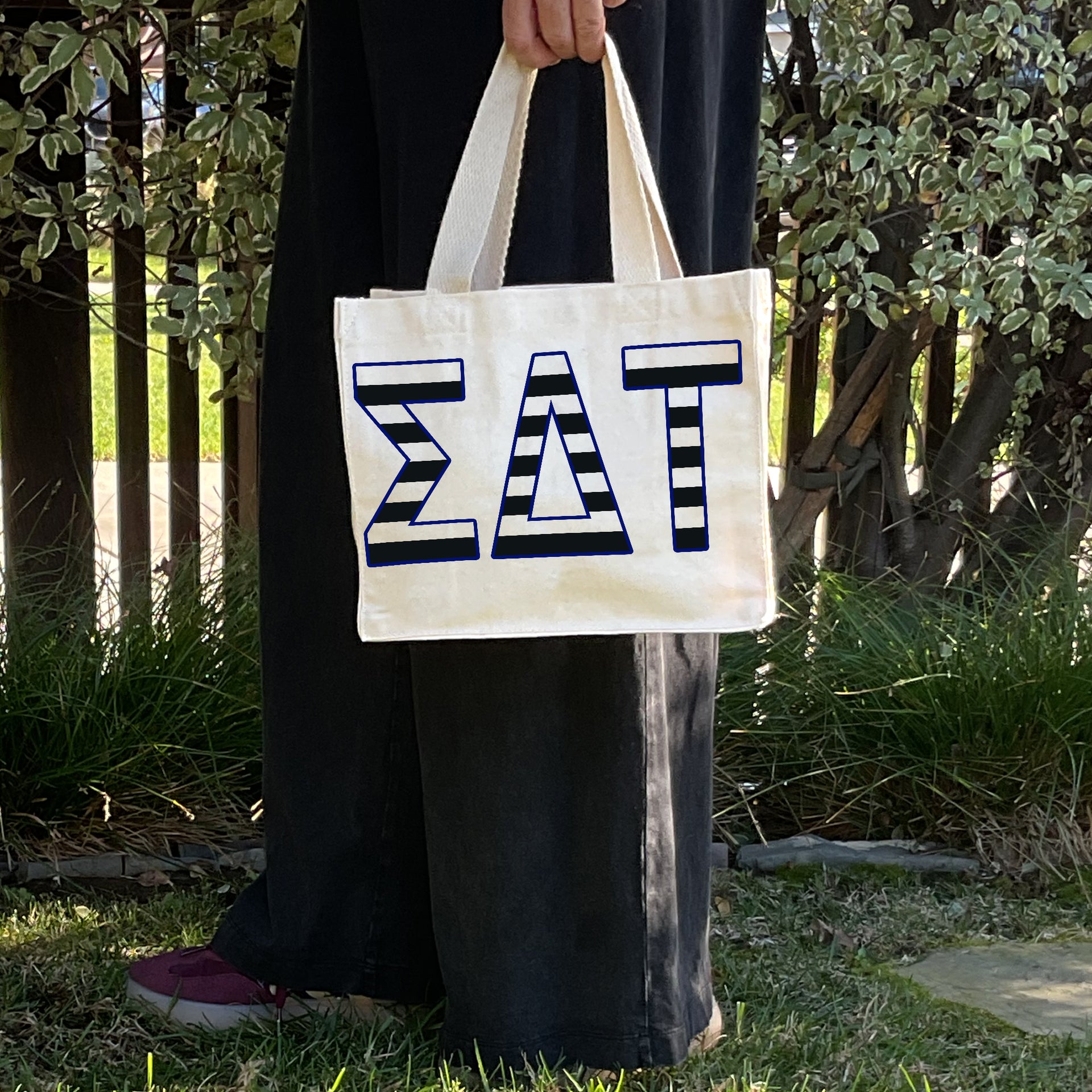 Model carrying the Sigma Delta Tau small black and white stripe tote.