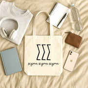 Sigma Sigma Sigma small canvas tote bag with striped Greek letters styled in a flat lay with everyday essentials