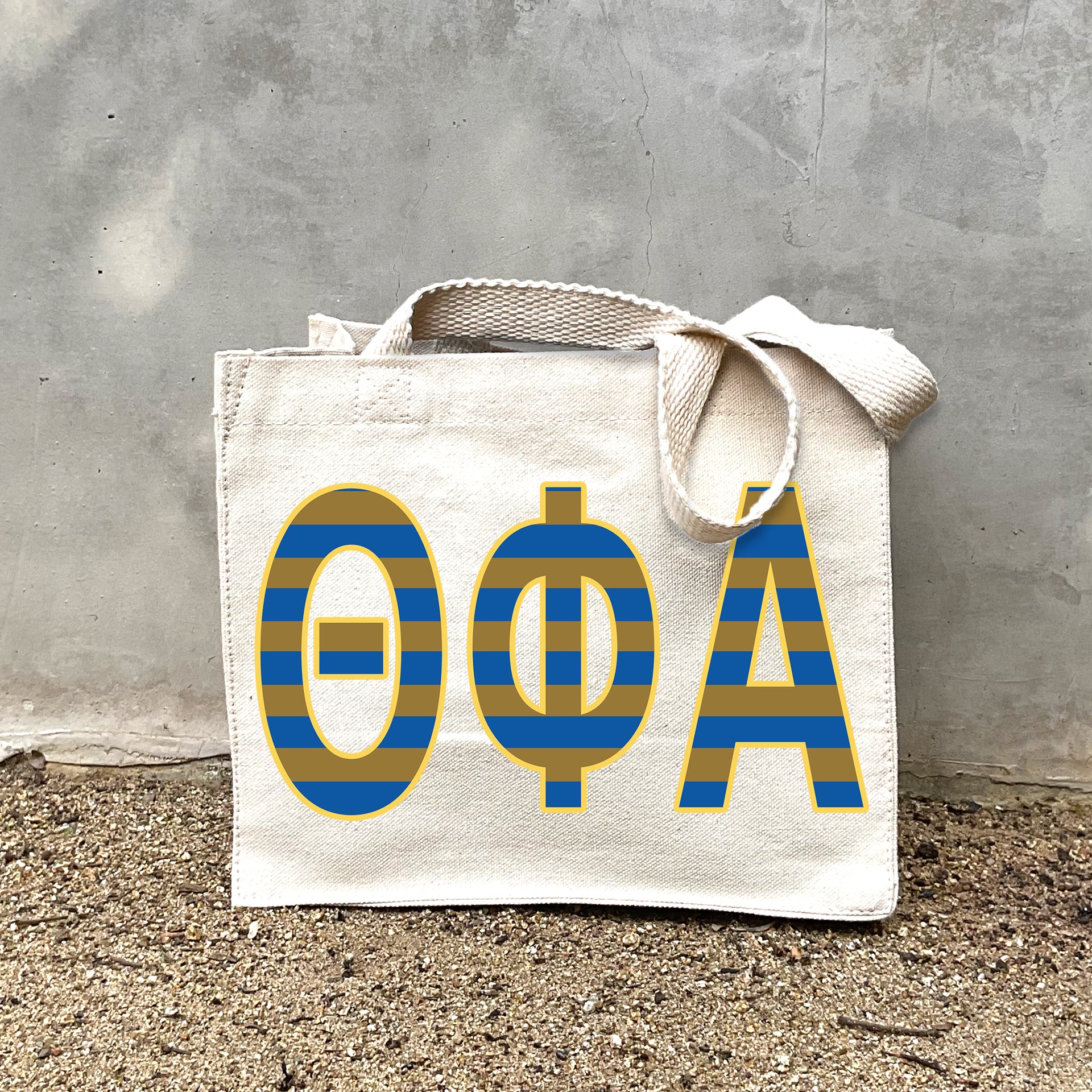 Model carrying the Theta Phi Alpha Greek letters in sorority colors small striped tote.