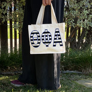 Model carrying the Theta Phi Alpha small black and white stripe tote.