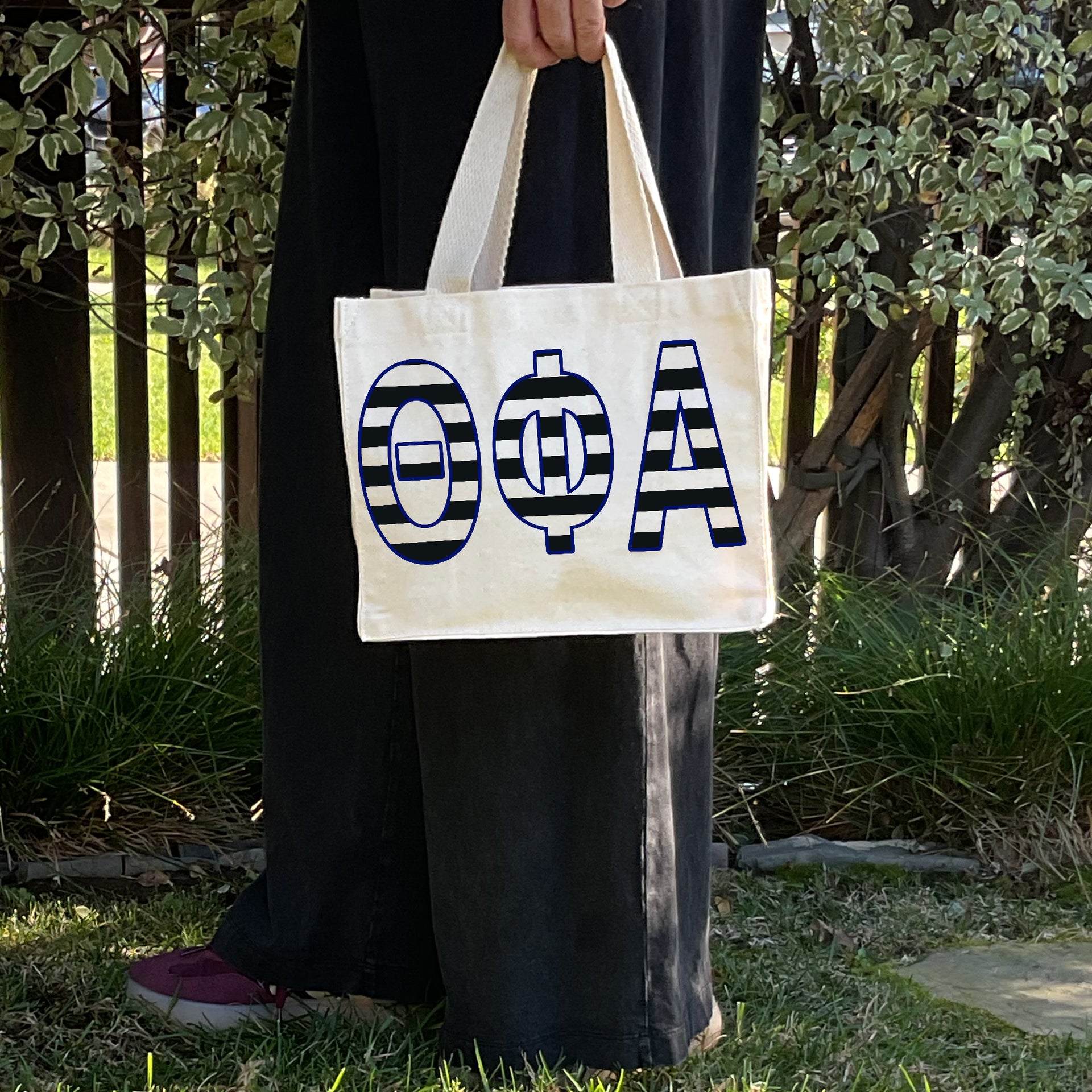 Model carrying the Theta Phi Alpha small black and white stripe tote.