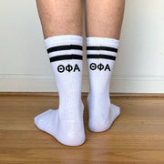 White crew socks with black stripes featuring "???" Greek letters printed on the back.