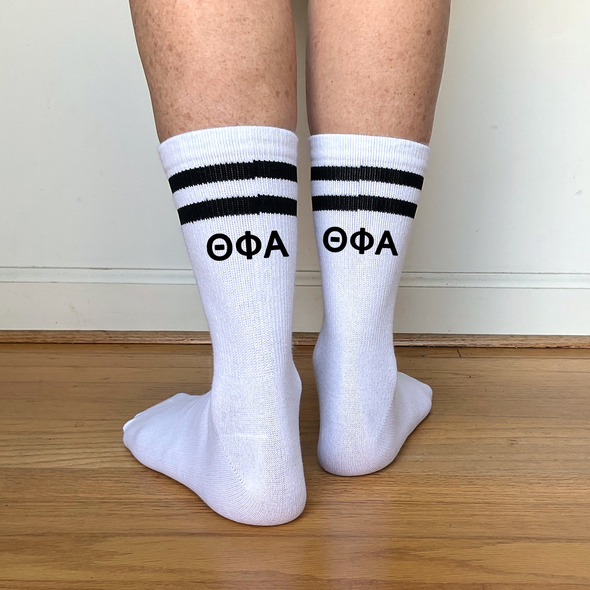 White crew socks with black stripes featuring "???" Greek letters printed on the back.