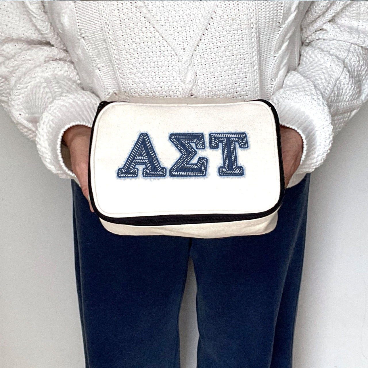 Alpha Sigma Tau canvas pouch with AST Greek letters in denim-style print, held by a sorority sister.