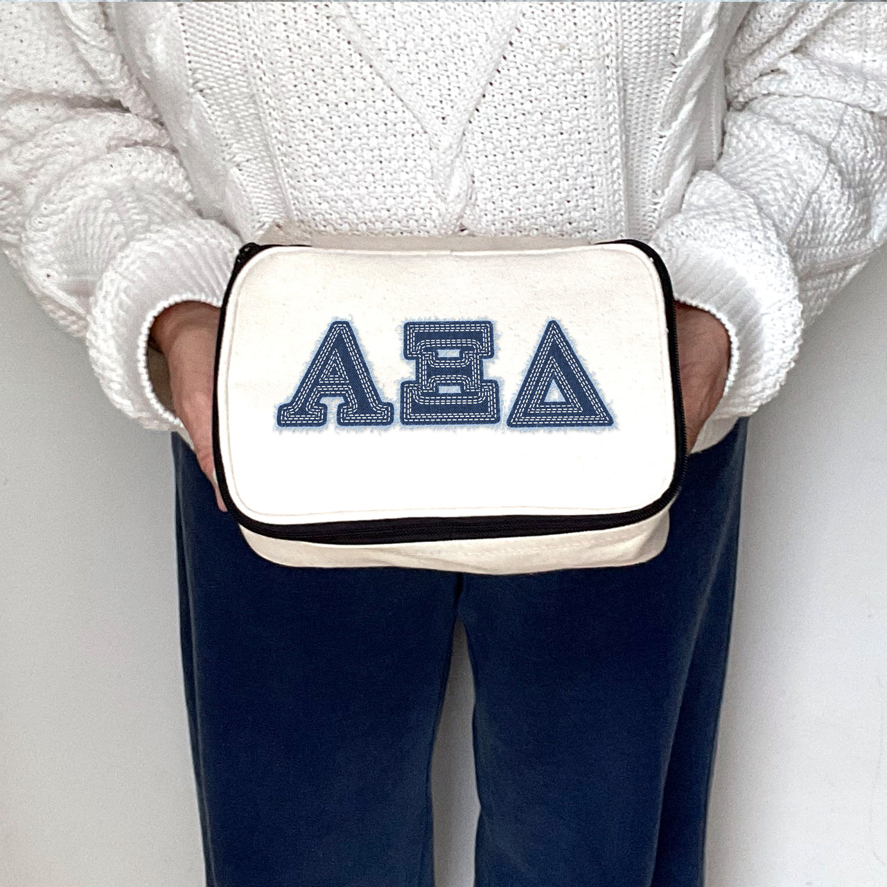Alpha Xi Delta sorority cosmetic bag printed with denim-style AXiD letters, held and shown up close.