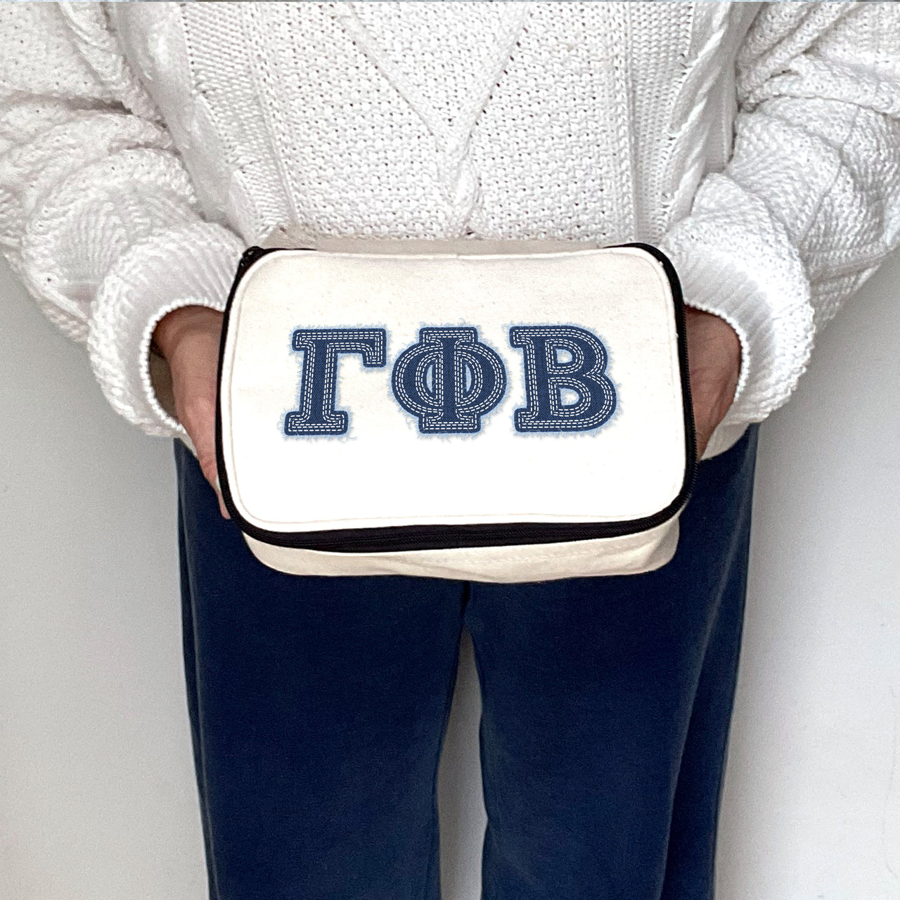 Gamma Phi Beta sorority member holding a Gamma Phi cosmetic bag with bold denim-style letters.