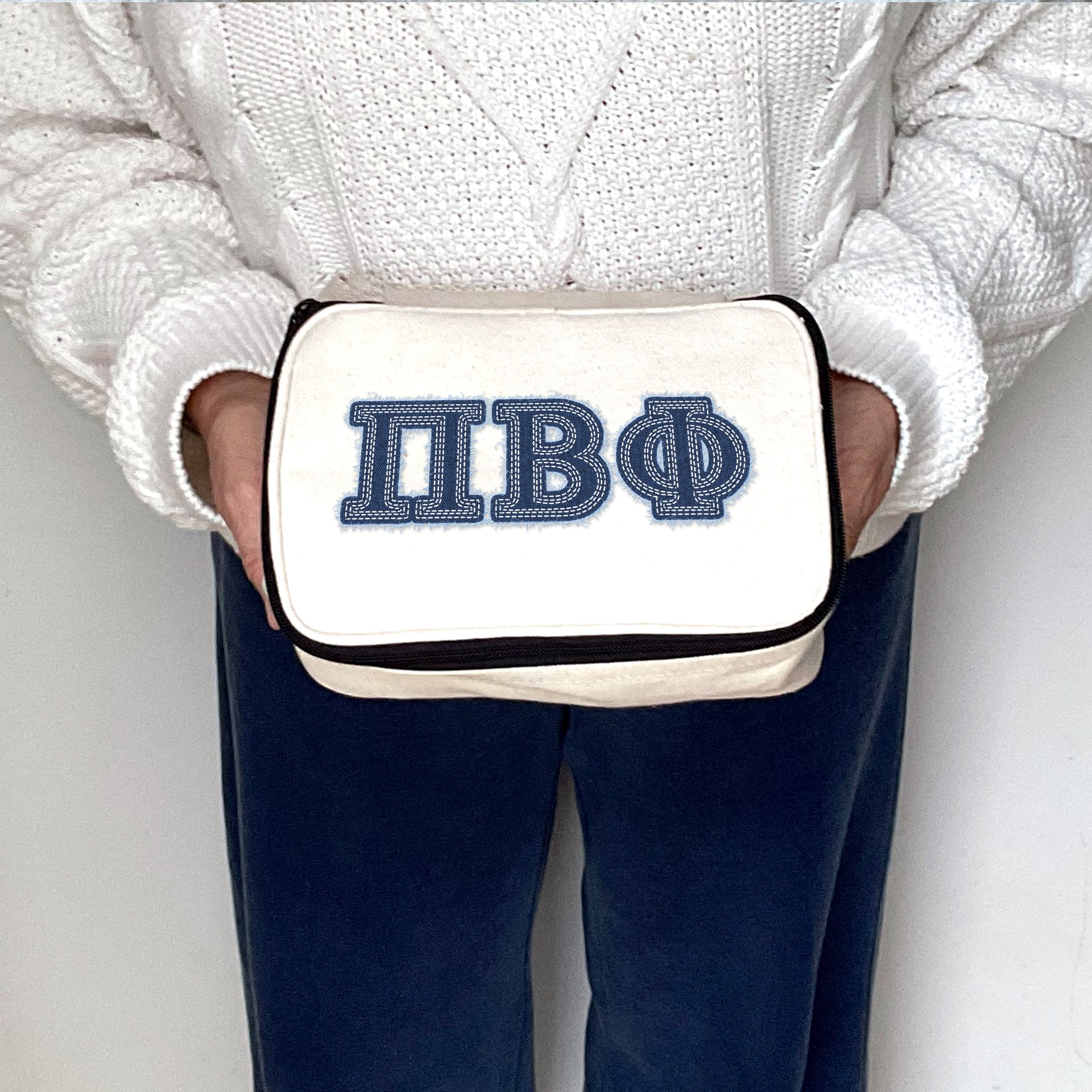 Pi Beta Phi Pi Phi makeup bag with printed denim-style Greek letters, held and presented by a member.