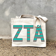 Model carrying the Zeta Tau Alpha Greek letters in sorority colors small striped tote.