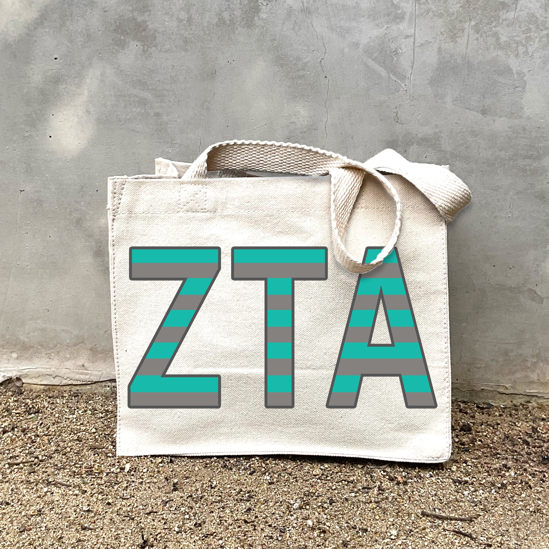 Model carrying the Zeta Tau Alpha Greek letters in sorority colors small striped tote.