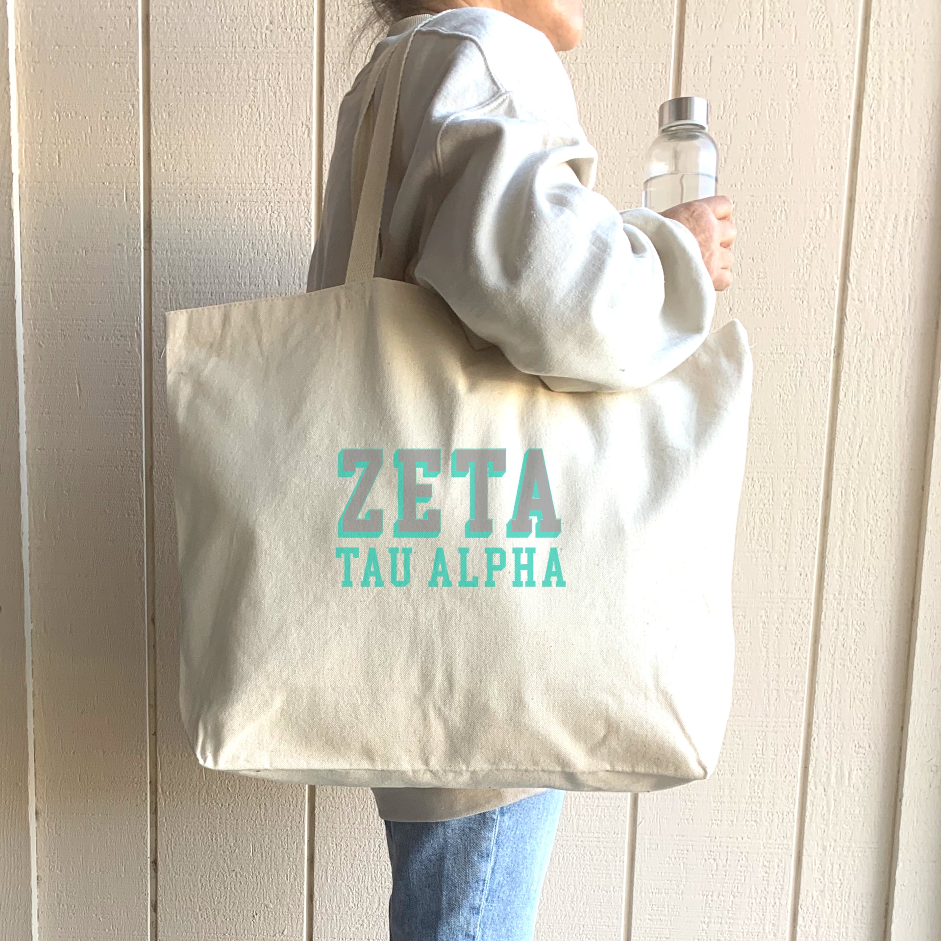 Zeta Tau Alpha tote bag with dimensional sorority letters, carried over the shoulder of a woman in ZTA gear.