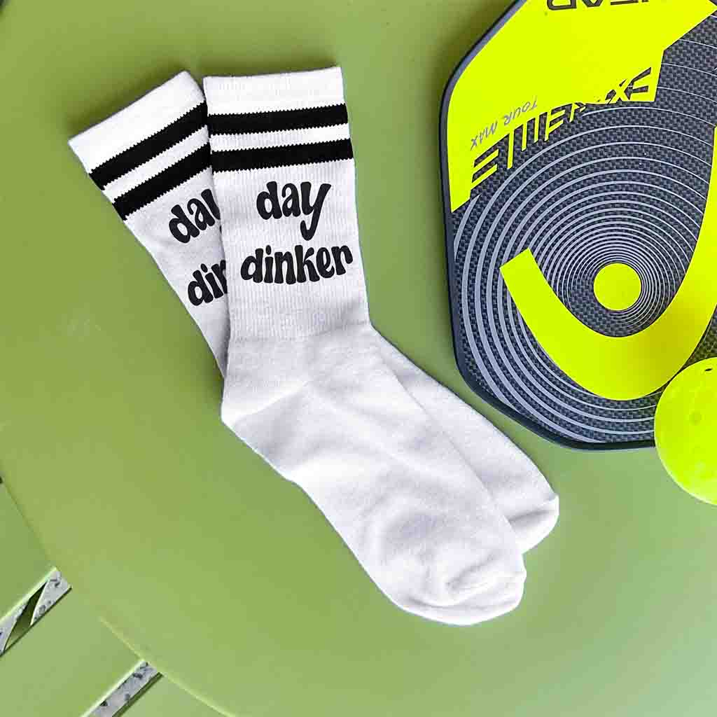 Day Dinker is custom printed on the side of the white cotton crew socks with black stripes.