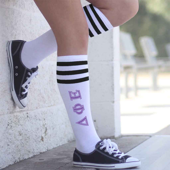 Delta Phi Epsilon sorority letters digitally printed on black striped knee high socks